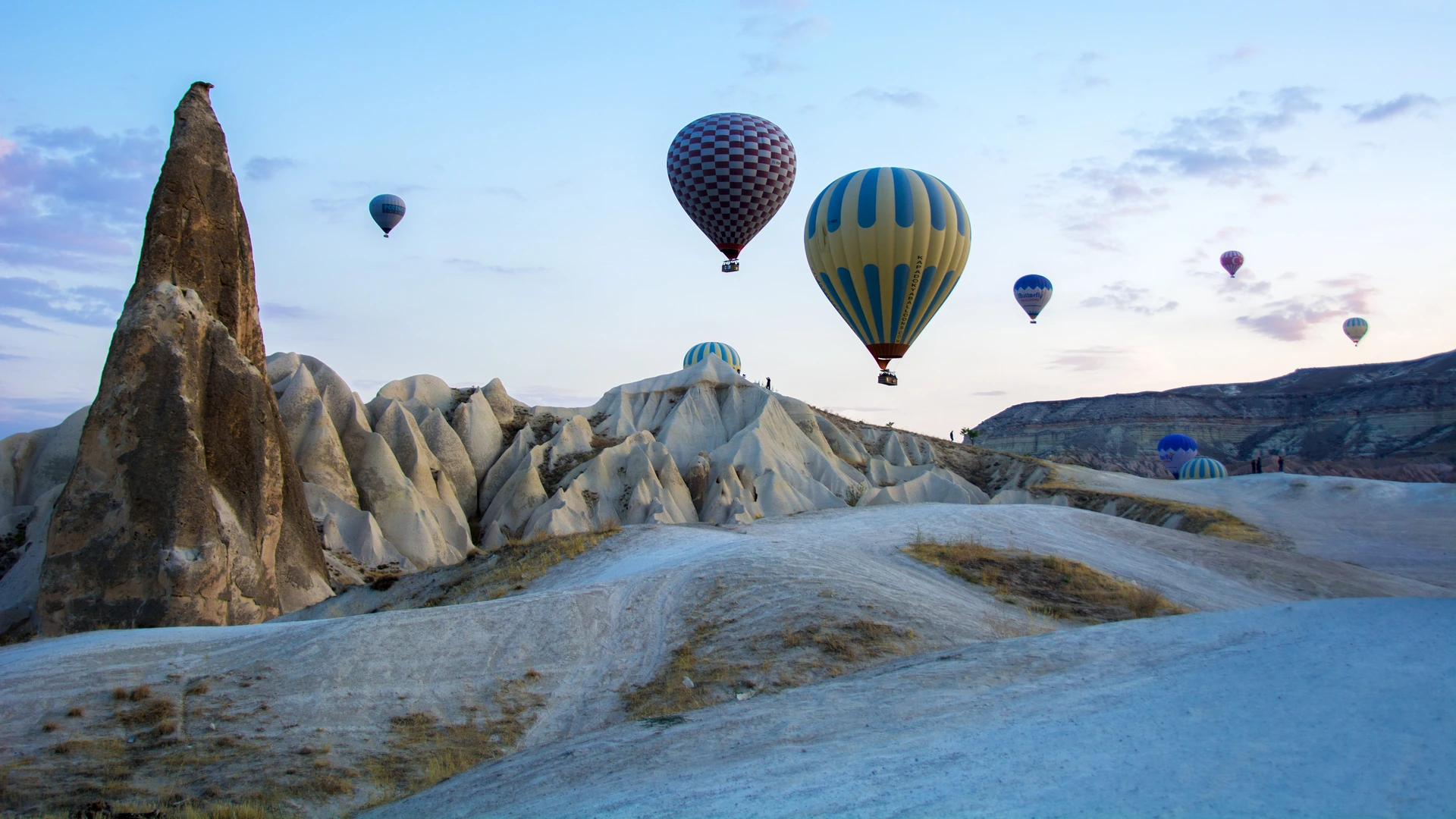 Hot air balloons rising between fairy chimneys.